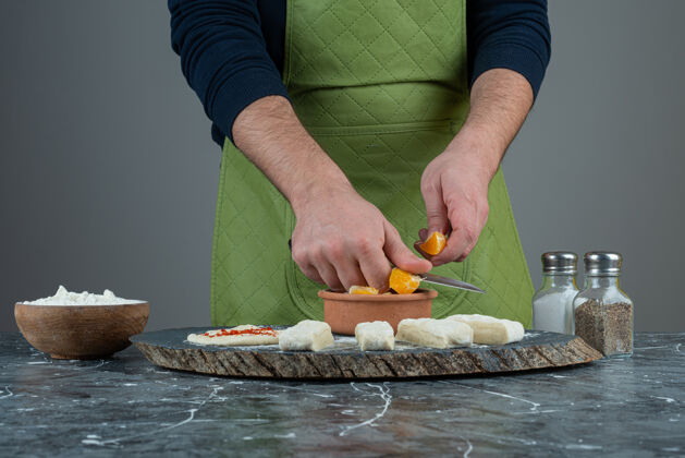 碗男厨师在大理石桌上把橘子切成块男人面粉手