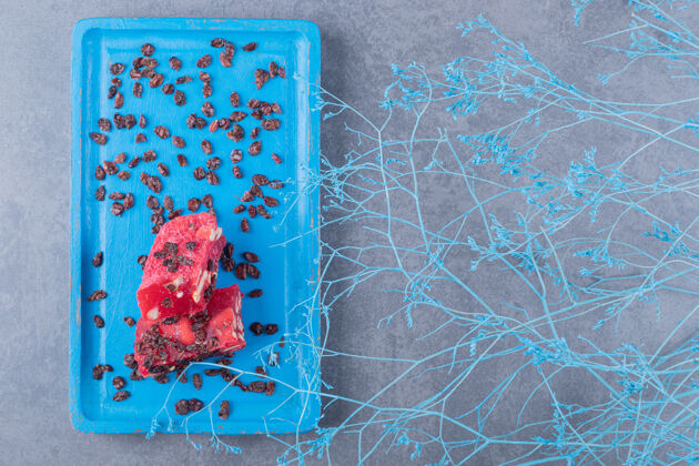 节日蓝色木板上的土耳其美食拉哈特勒库姆和干葡萄干俯视图小吃立方体水果