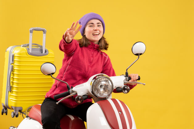 轻便摩托车前视图快乐的小女孩骑着轻便摩托车 伸出三个手指成人快乐人