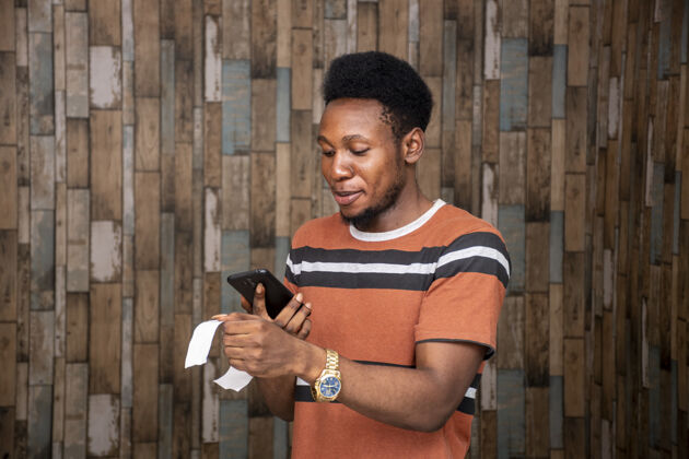 兴奋年轻的非洲男性正在用智能手机拍一张纸条的照片手机在线表达