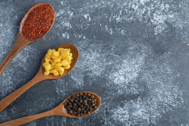 谷物在大理石表面放上玉米粒 胡椒粉和胡椒粉的木勺烹饪顶视图有机