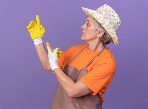 手套焦急的上了年纪的女园丁戴着园艺帽和手套指着紫色的一边看着急女帽子
