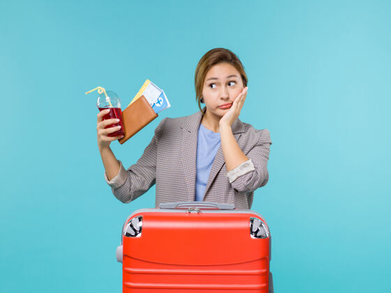 成人前视图女性在度假举行果汁与机票上蓝色背景旅行度假海上飞机人航行看法