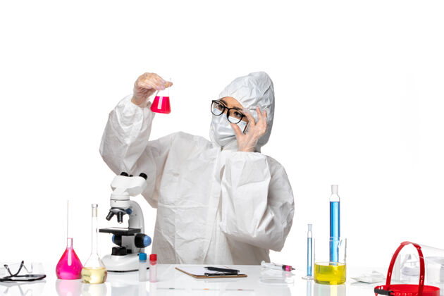 化学前视图穿着特殊防护服的女化学家拿着白色背景上的红色溶液科维化学病毒实验室保持视图病毒