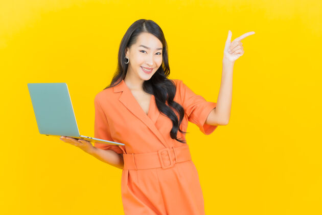 肖像肖像美丽的亚洲年轻女子微笑着用黄色笔记本电脑人员年轻人成人