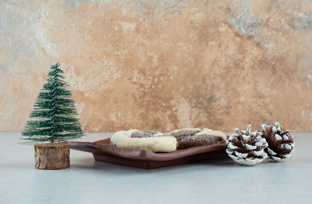 糕点一个深色的盘子 里面有两块美味的饼干 松果和圣诞树面包房圣诞树美味