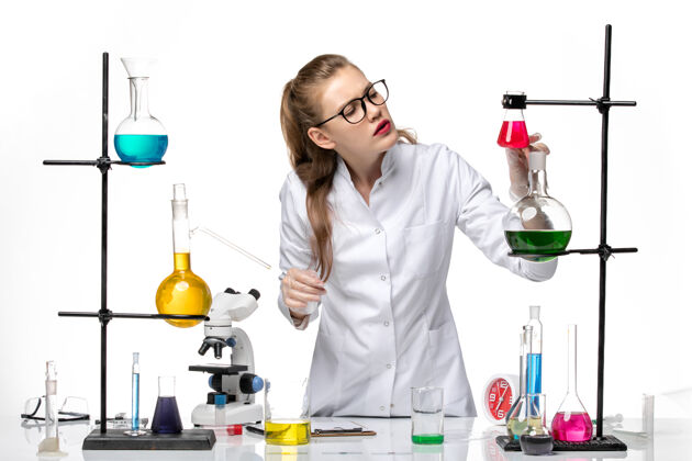 人前视图穿着医疗服的女化学家在工作过程中用白色背景上的溶液化学大流行病毒过程医学化学