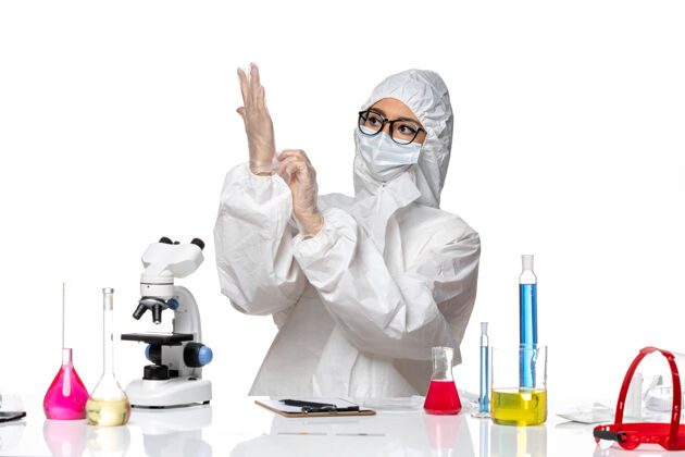 健康前视图穿着特殊防护服的女化学家戴着手套坐在白色背景上化学大流行病毒西装医学流行病