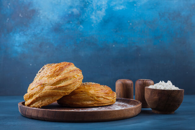 早餐蓝色表面有种子的甜糕点木盘有机面包皮传统
