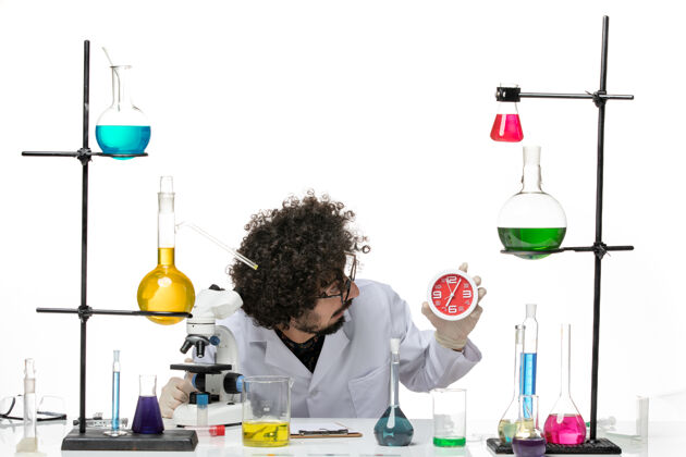 病毒正面图穿着医疗服的男科学家在白色的桌子上拿着红色的时钟烧杯实验室红色
