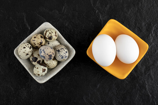 有机三个鹌鹑蛋和鸡蛋在黑色的表面烹饪食品碗