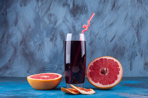 切块一杯新鲜的果汁和蓝色背景的西柚片水果果汁新鲜