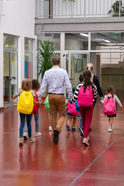 肖像学生们背着明亮的背包 牵着老师的手 穿过学校的走廊走廊成人年轻