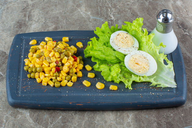 风味玉米沙拉旁边的切片鸡蛋放在生菜盘上 放在大理石表面上玉米沙拉美味美味