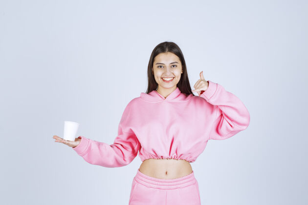 人类穿着粉色睡衣的女孩捧着咖啡杯 享受着咖啡的味道休闲好服装