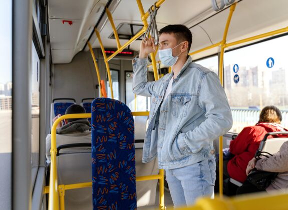 人年轻人戴着口罩坐公交车城市病毒旅行