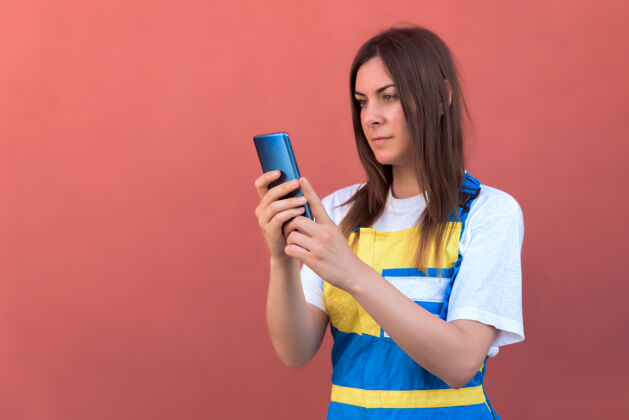 背景一个年轻女性用智能手机摆姿势的特写镜头漂亮相机人物