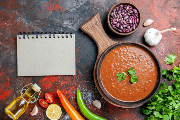 笔记本经典番茄汤倒油瓶豆和笔记本放在色彩斑斓的切菜板上混合黑板午餐