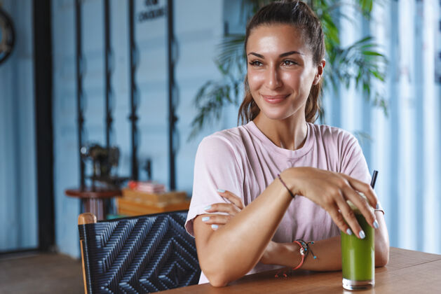 放松美丽的微笑的女人在度假 享受天堂度假村 坐在咖啡馆使用手机和喝健康的冰沙女孩咖啡馆积极