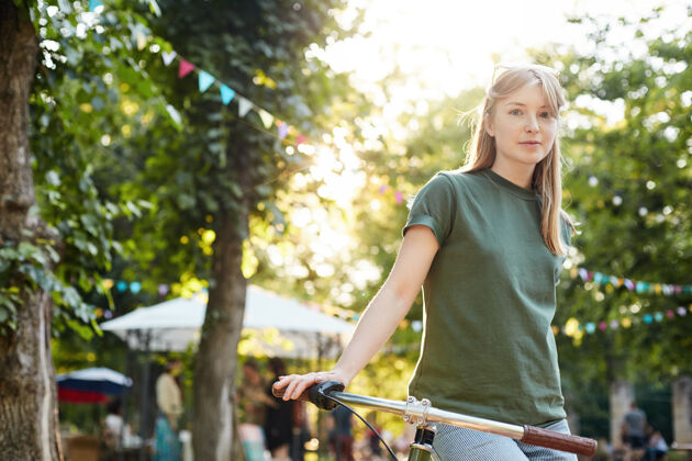 青年骑自行车的女人城市公园里 坐在自行车上困惑微笑的年轻女人的画像自行车积极表达