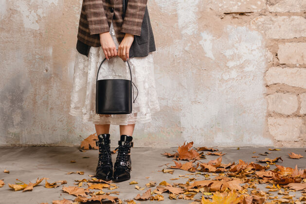 优雅一个穿着夹克的时髦女人穿着靴子 在街上靠着墙走来走去秋天秋天女士