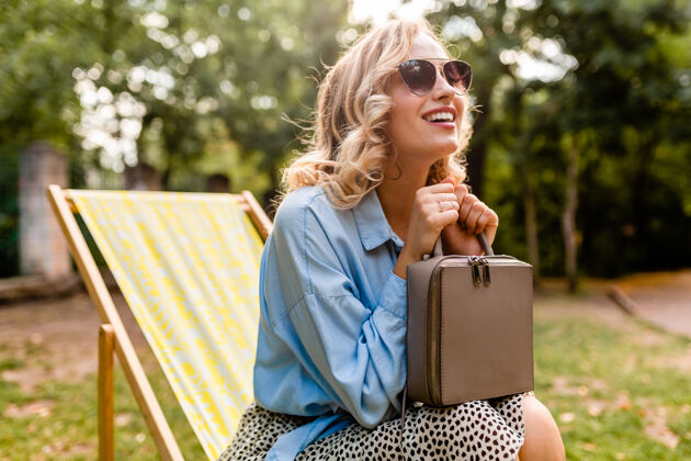 放松迷人的金发微笑的女人坐在躺椅上穿着夏天的衣服积极夏天春天