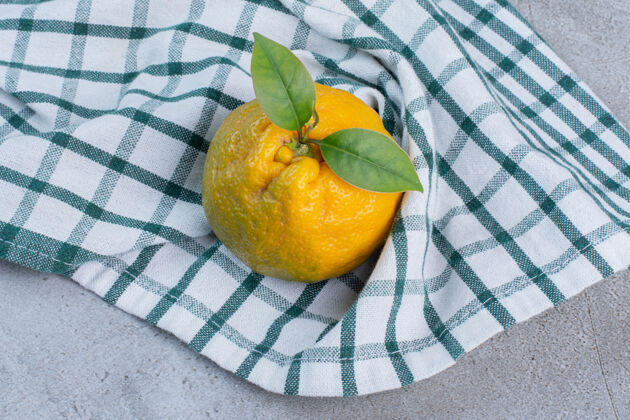 新鲜在大理石背景上的毛巾上放一个橘子营养美味饮食