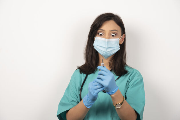工作年轻医生带着医用口罩在白色背景上准备注射注射妇女医疗