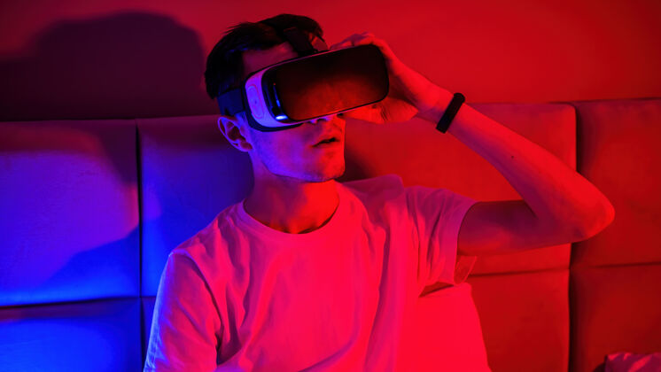设备这个年轻人戴着一副蓝色和红色的虚拟现实眼镜 躺在床上的房间里 给人留下了深刻的印象科学人虚拟现实