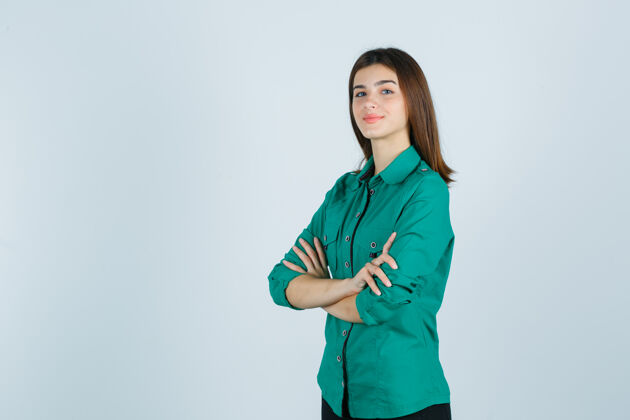 年轻美丽的年轻女士抱着绿色衬衫折叠的手臂 看着骄傲的前视图的肖像时尚表情西班牙裔