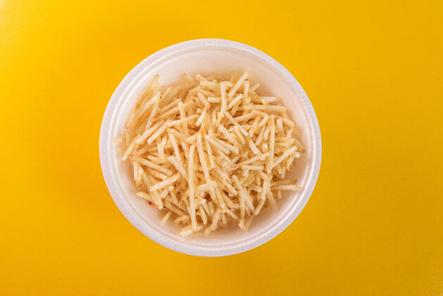 膳食白色的碗 黄色的背景上有土豆杆美食不健康的食物土豆薯条