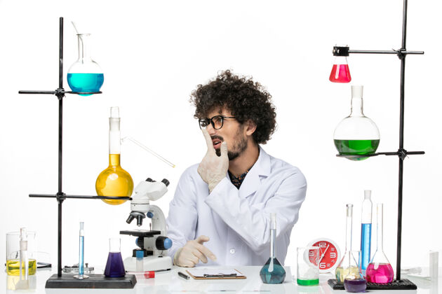 诊所前视图穿着医疗服的男性化学家正坐在桌子前面 在空白处放着溶液外套医生医学
