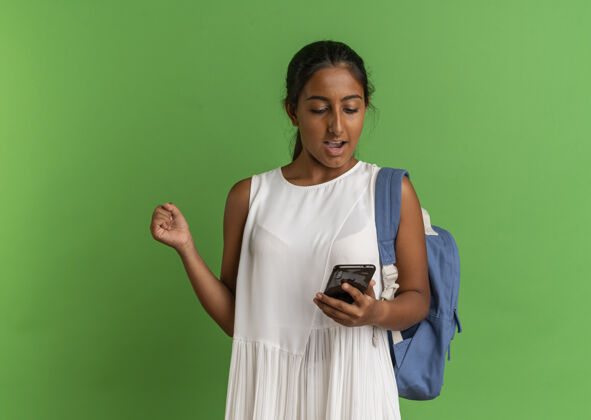 背包快乐的年轻女学生背着书包 拿着手机 看着手机 做着“是”的手势绿色年轻人穿