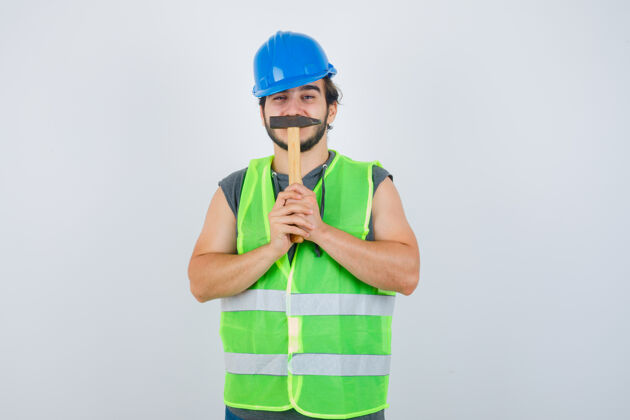 欢呼年轻的建筑工人穿着工装 嘴上拿着锤子 看上去很滑稽 正面照新年孩子年轻