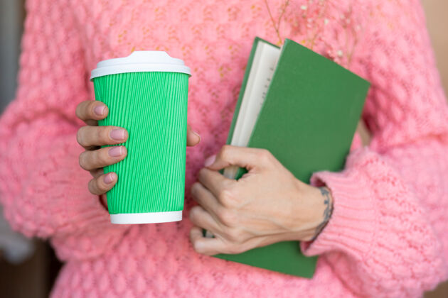 文学一个女人拿着一本打开的书 里面有一束干花和一杯咖啡开放花束手指
