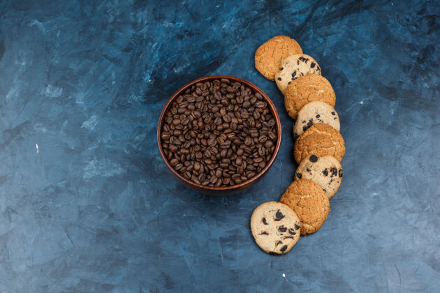 美味的把咖啡豆平放在碗里 在深蓝色的背景上放上不同类型的饼干水平饼干饼干巧克力