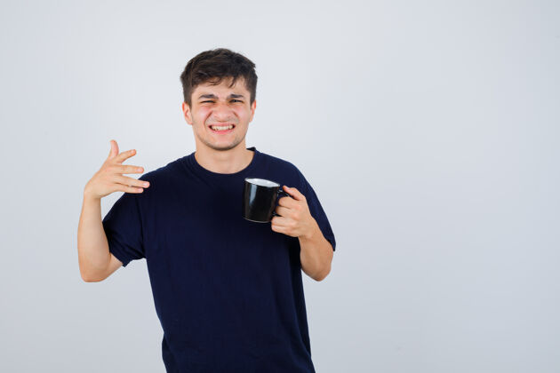 男人一幅年轻人拿着一杯茶的肖像 指着远处的黑色t恤衫 看不清前方的景色随意英俊惊奇