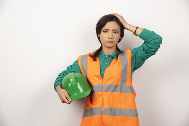 女性心烦意乱的女工程师抓着头 拿着白色背景的头盔女性工人建筑工人