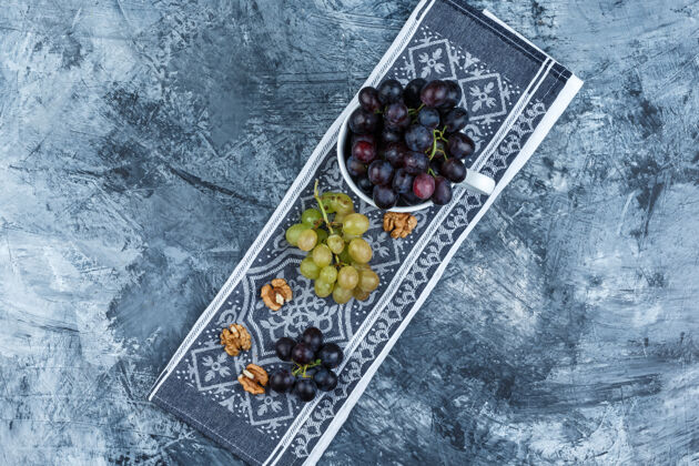 葡萄酒一些葡萄和核桃放在一个白色的杯子里 背景是垃圾和厨房毛巾 顶视图大季节果汁
