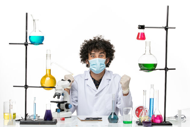 医生正面图：穿着白色医疗服 戴着口罩的男性化学家正坐在白色的空间里欢欣鼓舞化学实验室外套前面