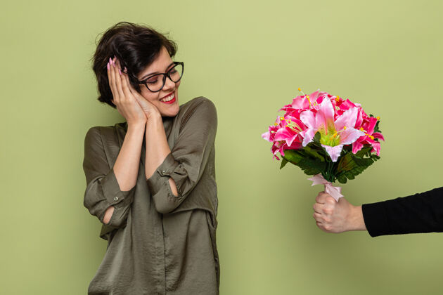 节日喜洋洋的短发女子在收到男友送的花束庆祝三八国际妇女节时 脸上露出惊喜和幸福的笑容鲜花欢呼微笑