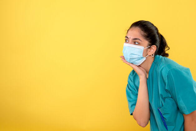 前面年轻女医生戴着医用口罩 手放在黄色墙上的下巴上人人封面