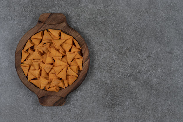 配料奶酪口味的锥形玉米片放在大理石表面的木制盘子里美味薯片美味