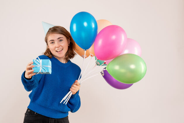 举行手持彩色气球和白色小礼物的年轻女性庆祝观点生日