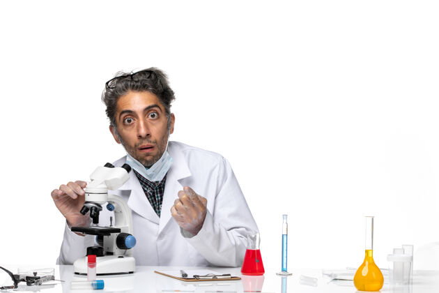 科学前视图穿着白色医疗服的中年科学家正在尝试使用显微镜专业化学观察