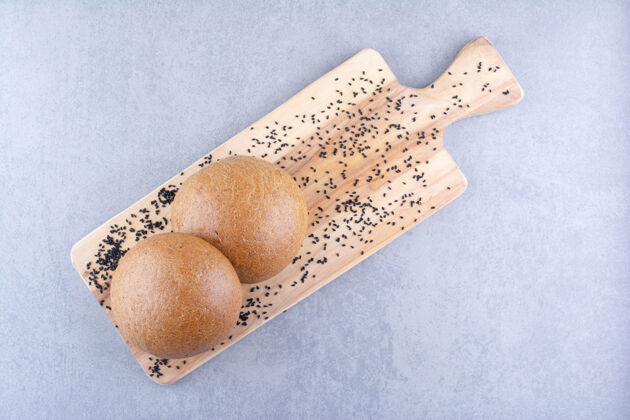 自制小木板上放着黑芝麻和汉堡包 放在大理石表面面包面粉板