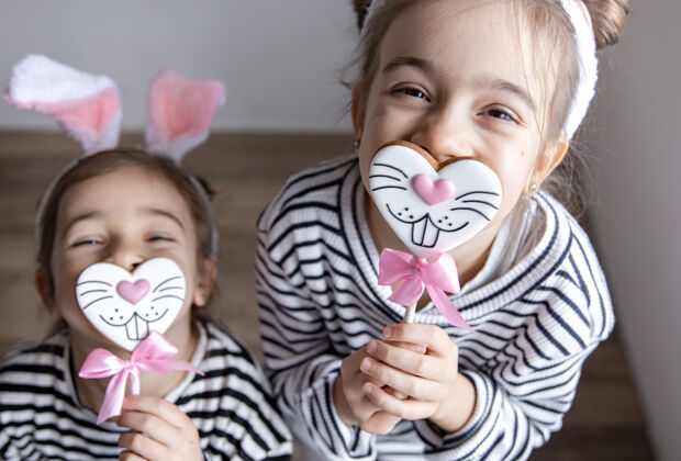 举行可爱的小姐妹们 带着复活节姜饼 兔子脸和兔子耳朵小耳朵年轻