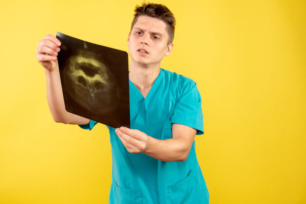 药正面图身穿医疗服的年轻男医生拿着黄色的x光片年轻男性医生人青少年