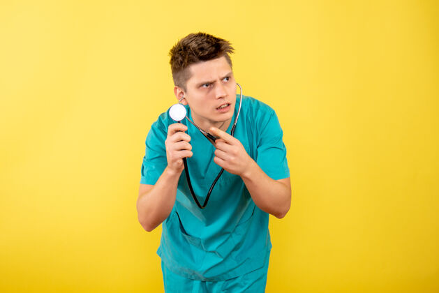 球员前视图年轻男医生穿着医疗服 黄色背景上有听诊器高尔夫球手药年轻的男医生