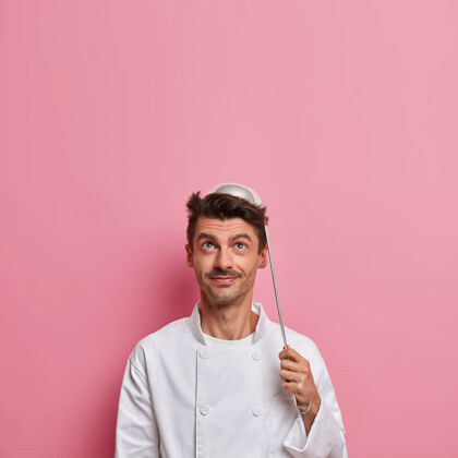 厨具正男厨师头上顶着勺子摆姿势 去准备汤 穿白色制服 拿着厨具 做餐厅菜 往上看美味小伙子咖啡馆